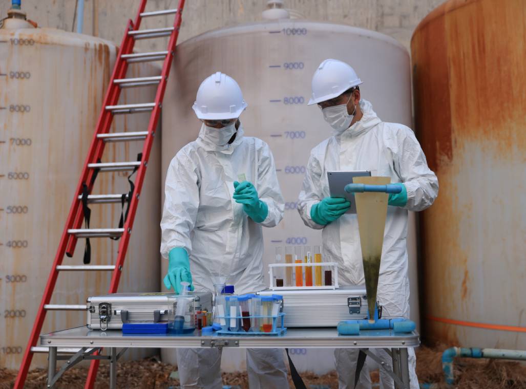 Scientists testing water samples in protective gear.