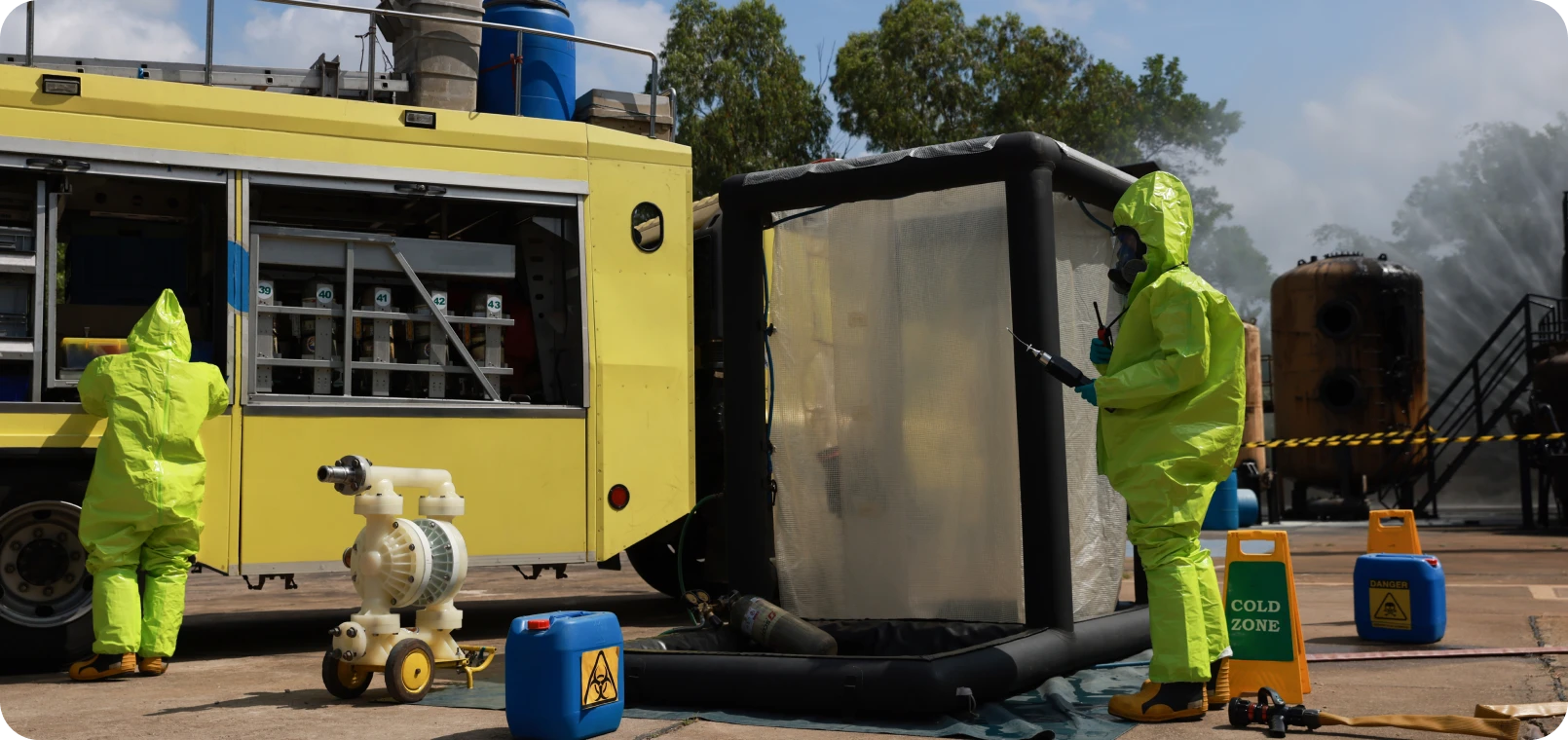 Hazmat team conducting decontamination procedure outdoors.