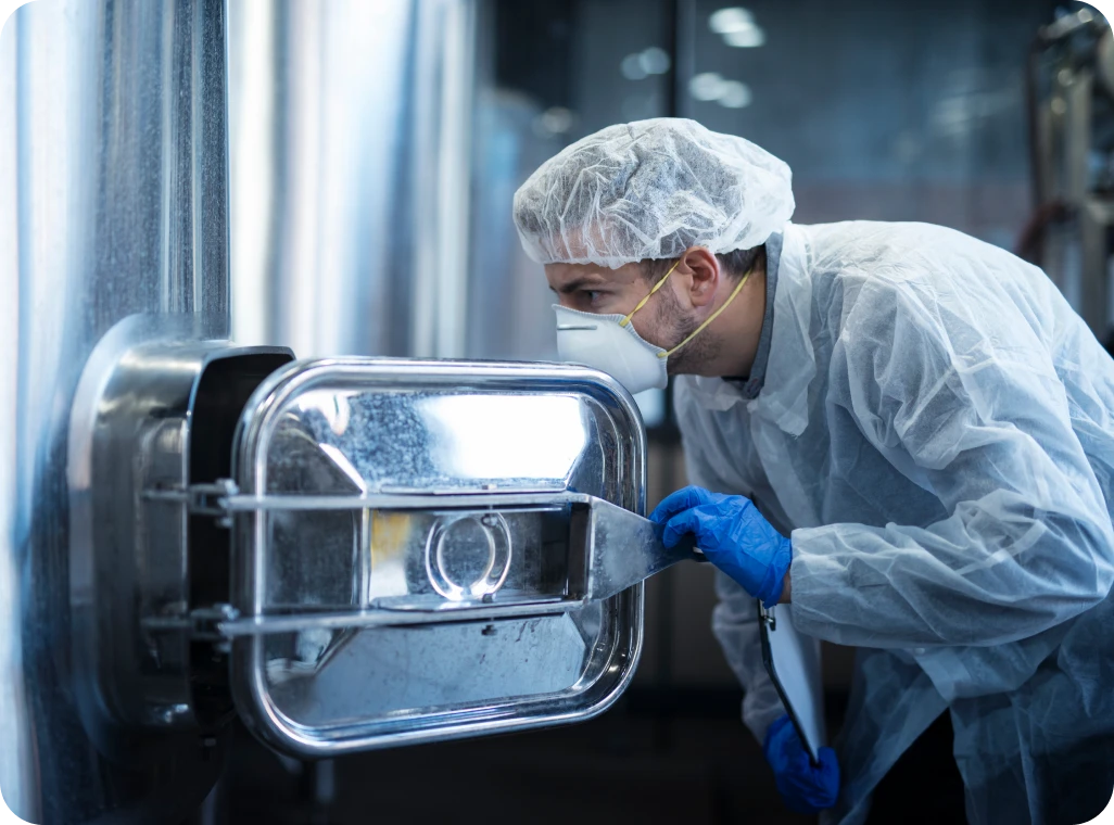 Worker inspecting stainless steel tank in factory.