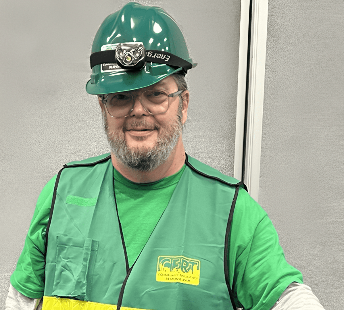 Man wearing a green safety vest and green helmet with a headlamp.